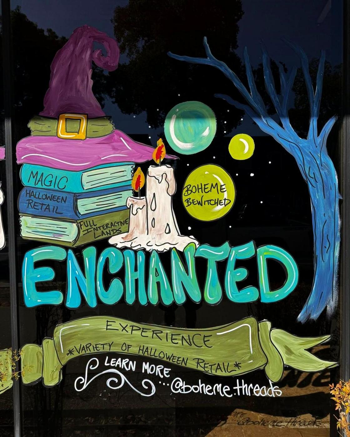 The painted shop window: a witch hat on a stack of spell books, and the word Enchanted