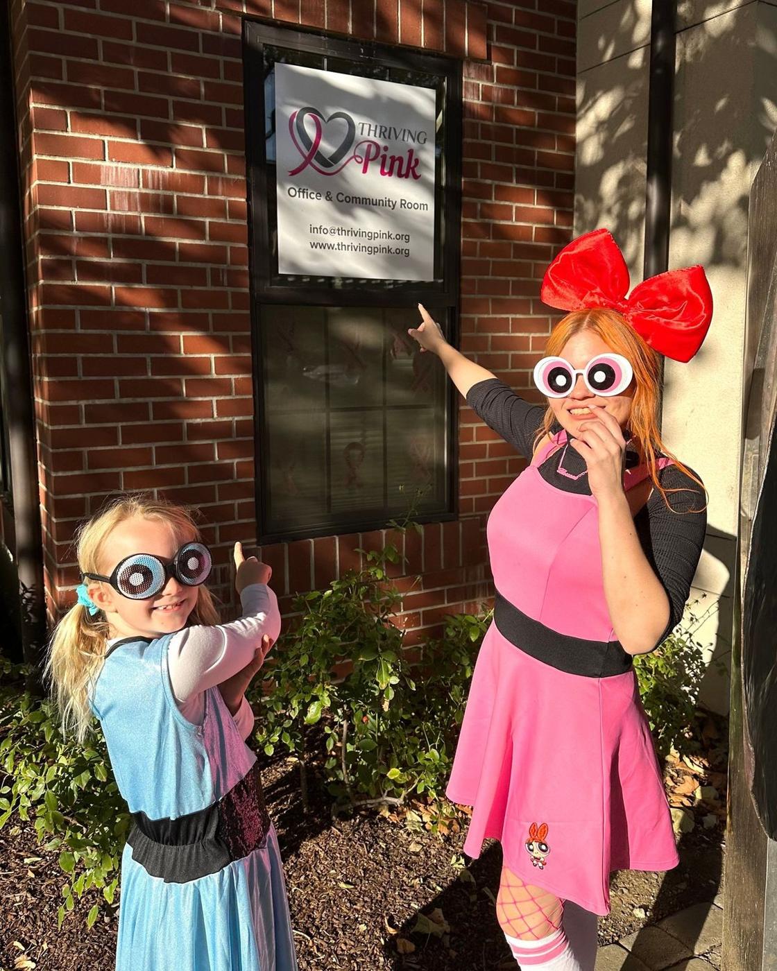 Two Powerpuff Girls pointing at the Thriving Pink office sign